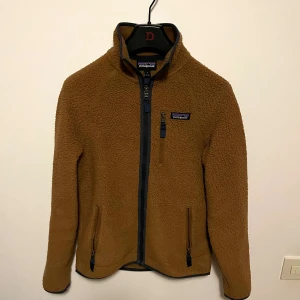 Patagonia fleece  - Brun Patagonia fleece i storlek S. Tillverkad i mjuk fleece med mörkblå detaljer och klassisk Patagonia-logga på bröstet. Storlek S, superbra skick. Nypris 1699 kr —> mitt pris 799 kr. Hör av dig vid minsta fundering. 