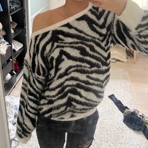 Zebramönstrad stickad tröja Dorothy Perkins - Säljer en stickad zebramönstrad tröja från Dorothy Perkins i svart och vitt. Tröjan har offshoulder-modell och är långärmad med en loose passform. Perfekt för dig som vill sticka ut lite extra med ett djurmönster.