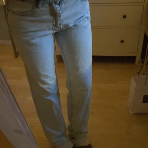 Ljusblå raka jeans - Säljer ett par ljusblå jeans med klassisk femficksdesign och raka ben. Jeansen har normal passform och är tillverkade i mjukt denimtyg. Perfekta för en avslappnad och stilren look.