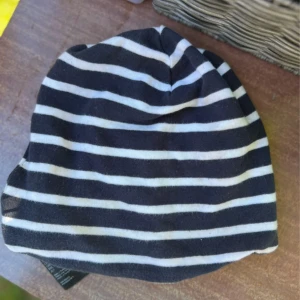 Randig svartvit mössa från H&M - Svart och vit randig mössa från H&M i mjuk bomull. Klassisk modell med horisontella ränder, perfekt för att hålla värmen under kyliga dagar. Passar barn i storlek 110/128, ålder 4-8 år.