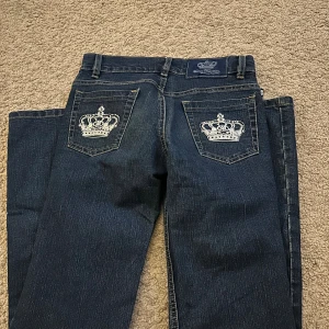 Blå jeans med kronbroderi bakfickor - Snygga mörkblå jeans från Rock & Republic med bootcut. Baksidan har vita kronbroderier på bakfickorna. 