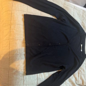 Svart kofta från KappAhl med knappar - En  svart kofta från KappAhl med v-ringning och knäppning framtill. 