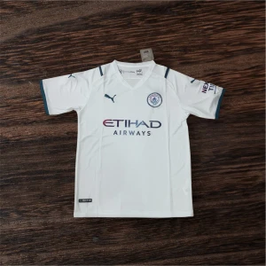Vit Manchester City fotbollströja Puma - Snygg vit Manchester City fotbollströja från Puma med klubbmärke på bröstet och Etihad Airways tryck. Kortärmad modell med mörkblå detaljer vid ärmslut och axlar. Perfekt för dig som vill representera City på planen eller i vardagen.