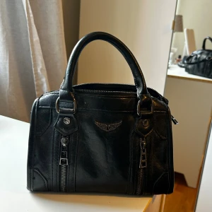 Svart handväska i skinn med dragkedjor - Svart handväska. Köpt på en marknad utomlands. Har använt den en gång så kvaliteten är som när jag köpte den. 