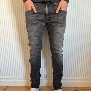 Replay Anbass grå jeans slim fit - Snygga Replay Anbass jeans i grå tvätt med slitningar och klassiska femficksdetaljer. Jeansen har smal passform och raka ben, tillverkade i mjukt jeanstyg. Perfekta för dig som gillar en modern och stilren look. Storlek: 30. Pris kan diskuteras men just nu 449kr! Hör av dig vid frågor