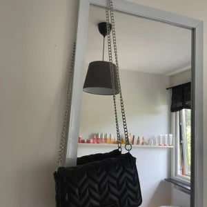 Svart quiltad axelväska från pull and bear - Snygg svart axelväska från pull and bear  med quiltad yta i sicksackmönster och silverfärgad kedja som axelrem. Väskan är tillverkad i skinnimitation och har en stilren, rektangulär form. Perfekt för att lyfta din outfit med en trendig detalj.