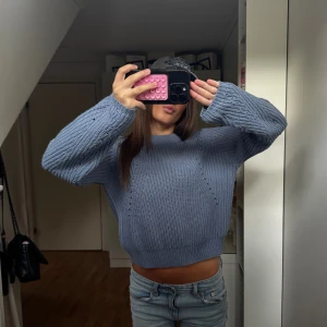 Blå stickad tröja  - Säljer en blå stickad tröja med loose fit och breda, långa ärmar. Tröjan har ett grovt ribbat mönster och en rundad urringning.