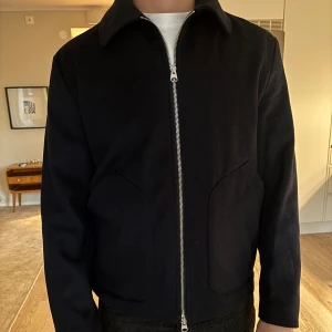 Mörkblå jacka med dragkedja från Doppelgänger - Säljer en stilren mörkblå jacka med dragkedja och klassisk krage. Jackan har långa ärmar och två framfickor. Perfekt som vårjacka