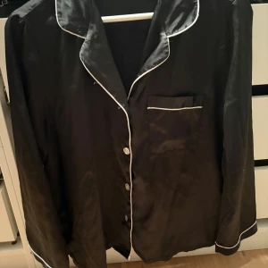 Fashion nova satinpyjamas   - Svart långärmad pyjamasskjorta från Fashion Nova i glansigt satinmaterial. 