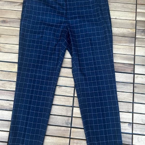 Mörkblå rutiga kostymbyxor H&M - Snygga mörkblå kostymbyxor från H&M med vitt rutmönster. Byxorna har normal passform, raka ben och klassiska fickor både fram och bak. Perfekta för en stilren look och passar till skjorta eller t-shirt.