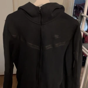 Svart Nike Tech Hoodie - Knappt använd Svart hoodie från Nike i storlek L. Säljer den eftersom den var för stor för mig och har ingen användning av den