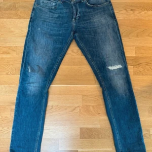 Dondup geroge  - Snygga blå skinny jeans från George med klassisk femficksdesign och slitningar på benen. Jeansen har skinny fit och är tillverkade i mjukt denimtyg med orangea sömmar och detaljer på bakfickorna. Perfekta för en avslappnad och trendig look. Storlek 34 sitter som 32 och 33