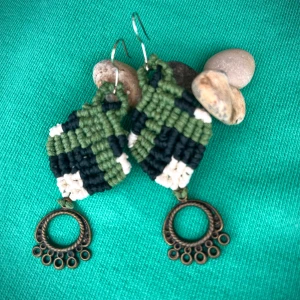 Handgjorda gröna makraméörhängen - Unika örhängen i makramé med gröna, svarta och vita ränder. Nedtill hänger en antikbronsfärgad metallring med små cirkeldetaljer. Perfekt för dig som gillar boho och handgjorda accessoarer.