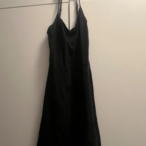 Svart och olivgrön klänningar - Två stilrena klänningar med smala axelband och lätt v-ringad halsringning. En är klassiskt svart och den andra i en snygg olivgrön nyans. 