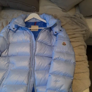 Ljusblå dunjacka från Moncler - Säljer en snygg ljusblå dunjacka från Moncler med modell Maya . Jackan är 3 år gammal använd en vinter. En väldigt varm jacka perfekt inför vintern! Tveka inte på att skriva vid frågor! Storlek 3. 
