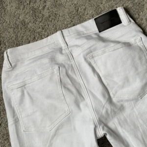 Vita jeans från Purple Brand - Säljer ett par fräscha vita jeans från Purple Brand, i storlek 32x32, utan några lappar (borttagna). Byxorna har klassisk femficksdesign, silverfärgad knapp och nitar i kopparfärg. De är raka i modellen och har en stilren look med normal passform. Perfekta för dig som vill sticka ut med en clean stil.
