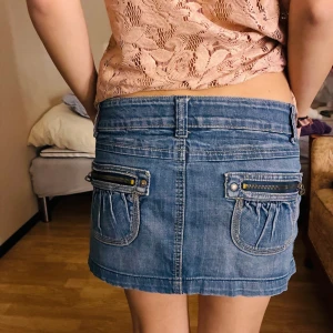 jeanskjol  - Snygg blå jeanskjol från Monica's Jeans med coola fickor och dragkedjedetaljer bak. Kjolen är i klassisk denim med knapp och dragkedja framtill, och har en kort passform som sitter perfekt på höften. Materialet är mjukt och stretchigt för extra komfort. Står storlek L men uppskattas som S då den passar modellen som bär s