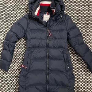 Marinblå dunjacka Tommy Hilfiger - Snygg och varm, marinblå dunjacka från Tommy Hilfiger med huva och dragkedja. Small modell som motsvarar S/M. Mycket bra skick!