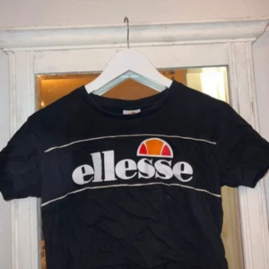 Svart Ellesse t-shirt med logga - Svart croppad t-shirt från Ellesse med logga över bröstet. Tillverkad i 100% bomull. Tröjan är i storlek S och knappt använd