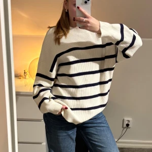 Randig vit stickad tröja - Säljer en oversized vit stickad randig tröja. Tröjan har en avslappnad passform, rund halsringning och långa ärmar. Perfekt för dig som gillar en chill och stilren look.