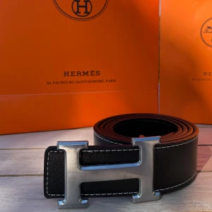 H Bälte Svart - Säljer ett svart bälte med ett silvrigt snyggt ”H” spänne. Bältet har en längd på 105 cm (storlek 42) och är Inte använt en enda gång, tveka inte att fråga! 💯👌