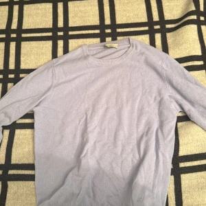 Ljuslila stickad tröja från Maglia Studio - En stilren ljuslila stickad tröja från Maglia Studio. Tröjan har rund halsringning, ribbade muddar och lång ärm. Perfekt för lager-på-lager och enkel att matcha med jeans eller kjol.