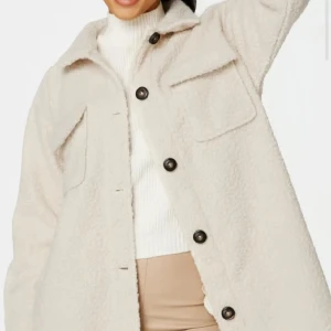 Beige teddyjacka med stora fickor - Säljer en beige teddyjacka med oversized passform och stora bröstfickor. Jackan har svarta knappar framtill och är tillverkad i mjukt fleece-material. Perfekt för dig som gillar en chill och trendig look under höst och vinter.
