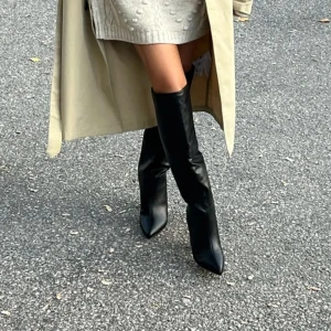 Svarta stövlar med klack  - Svarta stövlar med klack från Nelly som är slutsålda. Storlek 38, endast testade så i princip nya. Nypris 799kr. Skinnimitation, spetsig tå, knöhägt skaft, klackhöjd 10cm, skafthöjd 41cm skaftomfång på stl 38, 38cm.