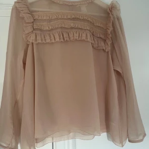Beige/ljus rosa volangblus med knappar - Säljer denna fina beige/ljus rosa blusen! Lite kort i armarna
