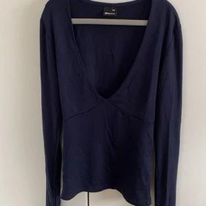 Mörkblå långärmad topp Gina Tricot - Snygg mörkblå långärmad topp från Gina Tricot i storlek XXS. Toppen har djup v-ringning och är tillverkad i mjuk bomull. Perfekt för dig som gillar enkel men stilren design. Testad 1 gång.