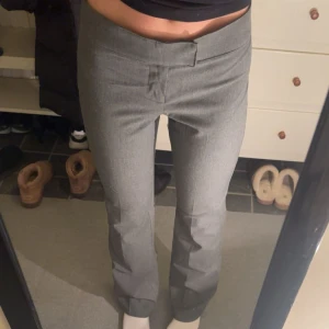 Grå kostymbyxor med rak passform - Snygga grå kostymbyxor med rak passform och låg midja. Byxorna har en stilren design utan synliga fickor eller detaljer, vilket ger en clean look. Perfekta för dig som gillar en enkel och modern stil. (Jag är 165 cm)