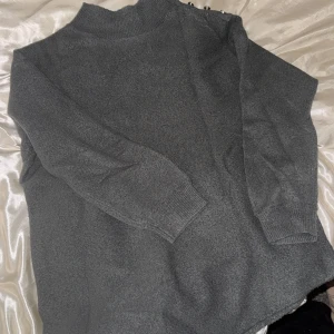 Grå stickad polo tröja  - Snygg grå stickad polo tröja med fina guldiga knappar vid kragen, lång och lite V formad nertill