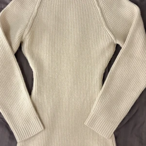 Stickad beige klänning från H&M XS - Supersnygg stickad klänning från H&M i beige ton, storlek XS. Klänningen har långärmade ärmar och är ribbstickad med en kroppsnära passform. Perfekt för dig som gillar enkel och stilren design med mjukt material.
