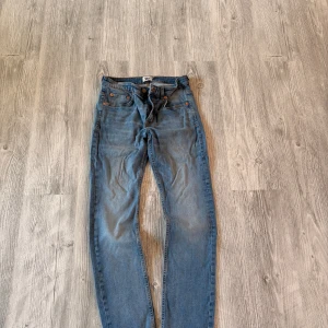 Blå slim fit jeans från 157, W32 L32 - Snygga blå jeans från 157 i modellen Slimmy. Klassisk femficksdesign, normalhög midja och smal passform. Jeansen har orangea sömmar och är tillverkade i mjukt denimtyg. Perfekta för dig som gillar en stilren och enkel look.