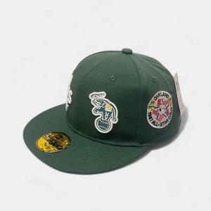 Grön Oakland A's keps från New Era - Grön 59FIFTY keps från New Era med Oakland A's logga framtill och broderade patches på sidorna. Platt skärm i samma färg och klassisk passform. Märkt med officiella MLB och World Series detaljer. Perfekt för dig som gillar baseball och streetwear.