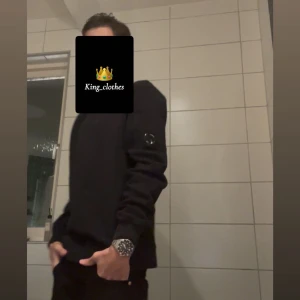 Svart sweatshirt från C.P. Company✨ - Svart sweatshirt från C.P. Company med klassisk rund hals och lång ärm. Tröjan har en ikonisk linsdetalj på vänster ärm och ribbade muddar vid ärmslut och nederkant. Perfekt för dig som gillar stilrena och snygga streetwear-plagg. | För mer frågor och funderingar skriv till mig.✨