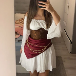 Pirat utklädnad halloween - En hel pirat outfit perfekt till halloween! 🎃 🏴‍☠️ Outfiten består av: - vit klänning i storlek XS - brun korsett i storlek S (som går att justera) -röd silkes scarf - guld kedja som man kan ha runt midjan Pris går att diskuteras vid snabb affär💕