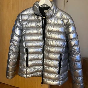 Moncler jacka - Intressekoll på min supersnygga silvriga jacka från moncler! Den är köpt secondhand, men väldigt bra skick, dock saknar den luvan. Som en jacka i storlek s, sitter snyggt!! Skriv för fler bilder