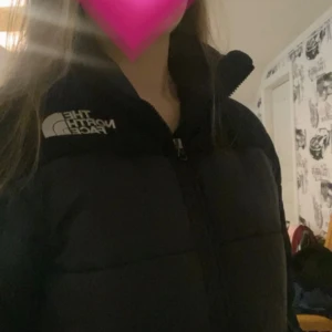 Svart pufferjacka från The North Face XS - Säljer en svart pufferjacka från The North Face i storlek XS men är stor i storleken så passar också s. Jackan har hög krage, dragkedja framtill och snörning i nederkant för att göra den mindre där nere. North face loggan på bröstet och baksidan. Perfekt för höst och vinter tiden. Köpt för 2000 kr