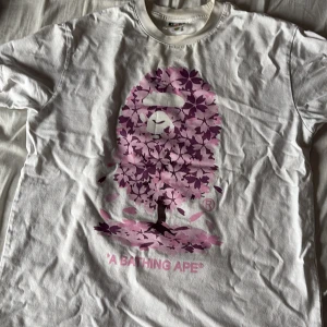 A BATHING APE (BAPE) - En snygg rosa T-shirt av A Bathing Ape ( BAPE), använd fåtal gånger nu på sommaren så den är i väldigt bra skick. Fraktas samma dag! Va inte rädd att höra av er vid snabb affär kan jag tänka mig sänka lite! (passar S/M/L) 