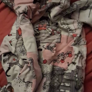 Pippi Långstrump klänning 110 - Supergullig klänning med Pippi Långstrump-tryck i vitt, rosa och röda detaljer. Klänningen har ett lekfullt mönster med motiv från Pippi och hennes värld, perfekt för dig som älskar Astrid Lindgrens klassiker. Mjuk och skön bomullskvalitet.