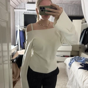 Vit offshoulder topp med vida ärmar - Säljer en vit offshoulder topp med långa, vida ärmar och figurnära passform. Toppen har en clean look med rak halsringning och är tillverkad i ett mjukt, stretchigt material som känns skönt mot huden. Perfekt för dig som gillar minimalistisk stil. Strlk 170