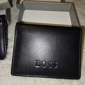 Svart plånbok från Boss & Armani - Snygga svarta plånböcker från Boss och Armani i stilren design. Tillverkade i slätt skinn med präglad logga på framsidan. Flera fack för kreditkort och sedlar, perfekt för dig som vill ha koll på korten. Kommer i original ask. 370kr st