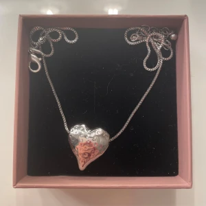 Halsband med hjärtformat hänge i silver - Snyggt halsband med ett stort hjärtformat hänge i blankt silverfärgat metall. Hänget har en cool, hamrad yta som ger det en unik look. Kedjan är tunn och har ett smidigt lås. Perfekt för dig som gillar statement-smycken med personlig touch.