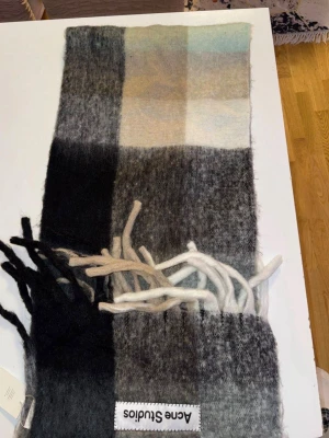 Rutig ullväst Acne Studios - Säljer en rutig väst från Acne Studios i mjuk ullmix. Västen har breda blockrutor i svart, grått, beige och ljusblått samt långa fransar nertill. Klassisk Acne Studios-label framtill. Perfekt för lager-på-lager och en cool, avslappnad look.