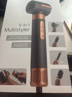 6-in-1 Multistyler hårverktyg - Säljer en 6-in-1 Multistyler i svart och roséguld med flera utbytbara borst- och locktillbehör. Perfekt för att skapa volym, lockar, vågor eller rakt hår. Har jonisering och Coanda-effekt för extra styling. Snygg design med smidiga knappar på handtaget.
