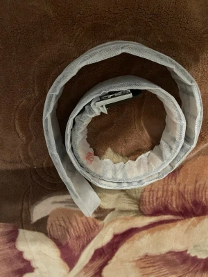 Rutig beige väst med spänne - Säljer en beige väst med klassiskt rutigt mönster i svart, vitt och rött. Västen har ett metallspänne framtill och är tillverkad i ett material som liknar skinn. Perfekt för dig som vill ha en stilren och trendig look. Den är 110 cm 