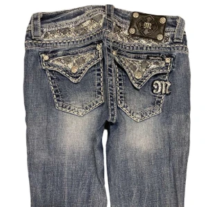 Low Waist Bootcut Miss Me Jeans - Ett par low waist bootcut Miss Me jeans i storlek 27. Jeansen är i fint skick men har tyvärr en liten fläck på låret men som knappt syns. Mått: Längd: 98 cm, Midja: 37 cm tvärs över och Innerben: 72 cm. Kontakta mig om du har frågor