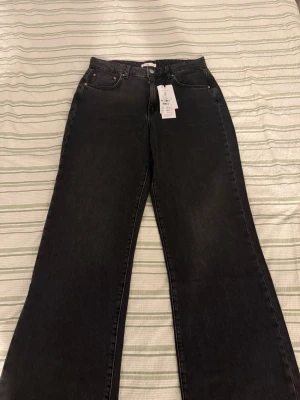 Svarta wide jeans med hög midja - Säljer ett par svarta wide jeans från Gina tricot i storlek 40. Byxorna har hög midja, klassisk femficksdesign och raka, vida ben. Materialet är jeans i bomull och de har en snygg mörk tvätt. Perfekta till sneakers eller boots.