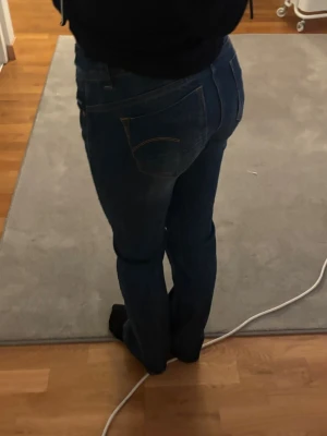 Blå jeans från G-Star RAW - Säljer ett par klassiska blå jeans från G-Star RAW med snygga kontrastsömmar och läderpatch bak. Modellen har normal passform och raka ben, samt fem fickor och knappgylf. Perfekta till vardagslooken och funkar året runt. 